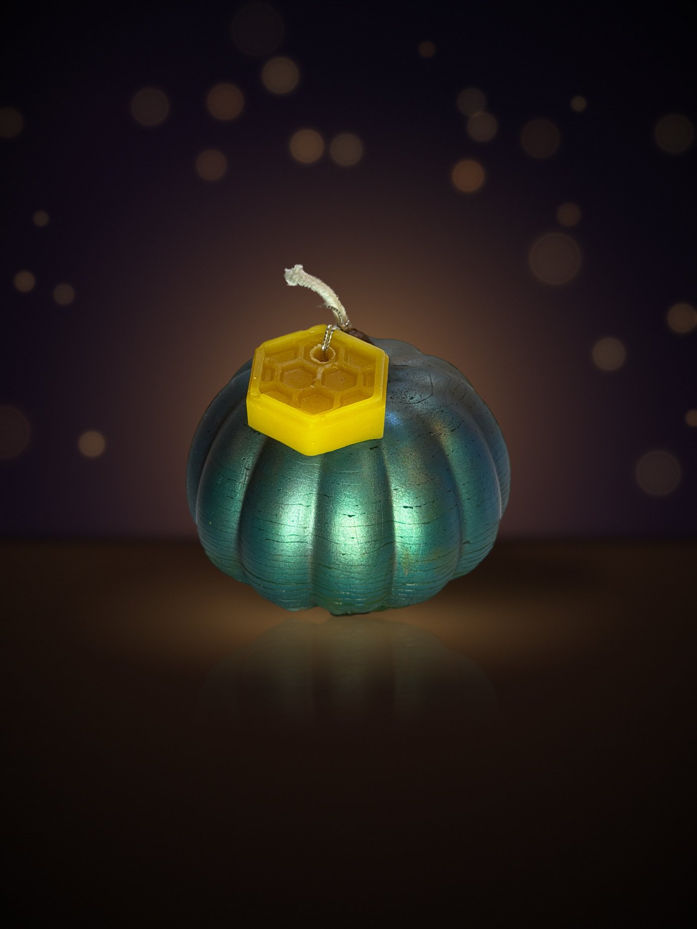 Maine beeswax pumpkin candle, big pumpkin shape, teal crackle, with honeycomb tag, warm candlelit background
