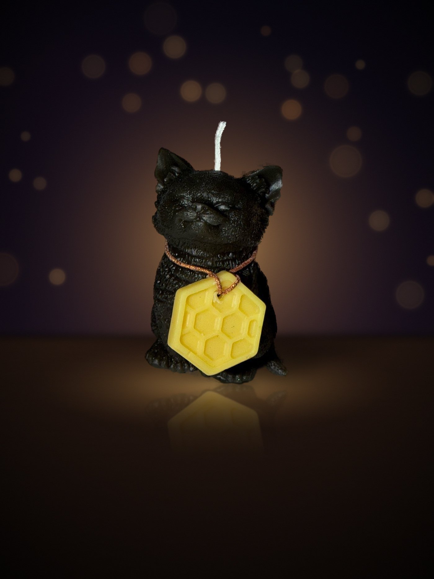 Maine beeswax RBF cat candle, front view with honeycomb charm, warm candlelit background