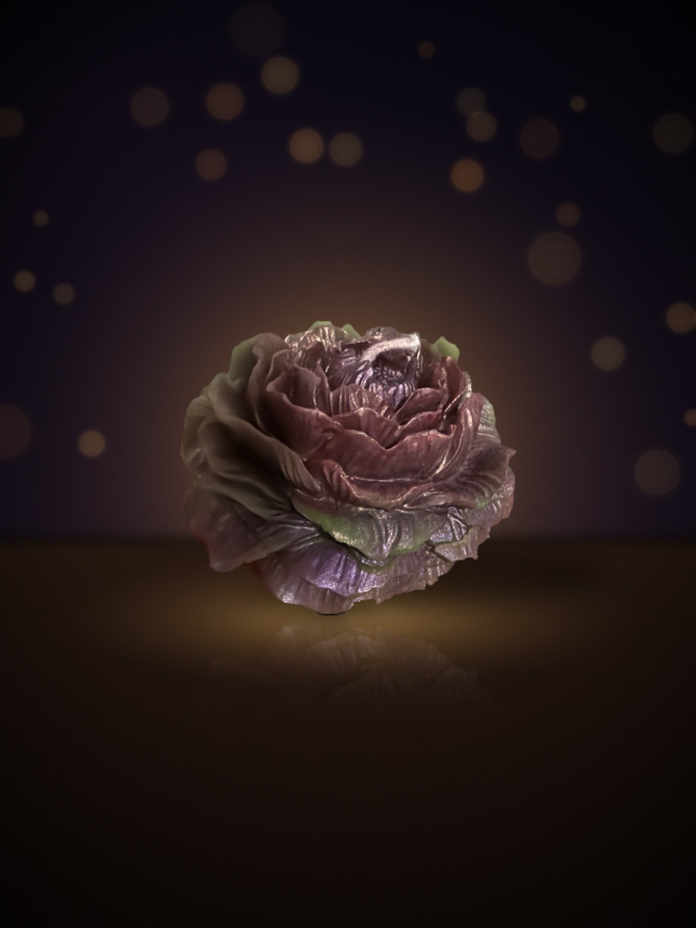 Maine beeswax rose candle in burgundy and mauve with sage-green petal tips, warm candlelit background