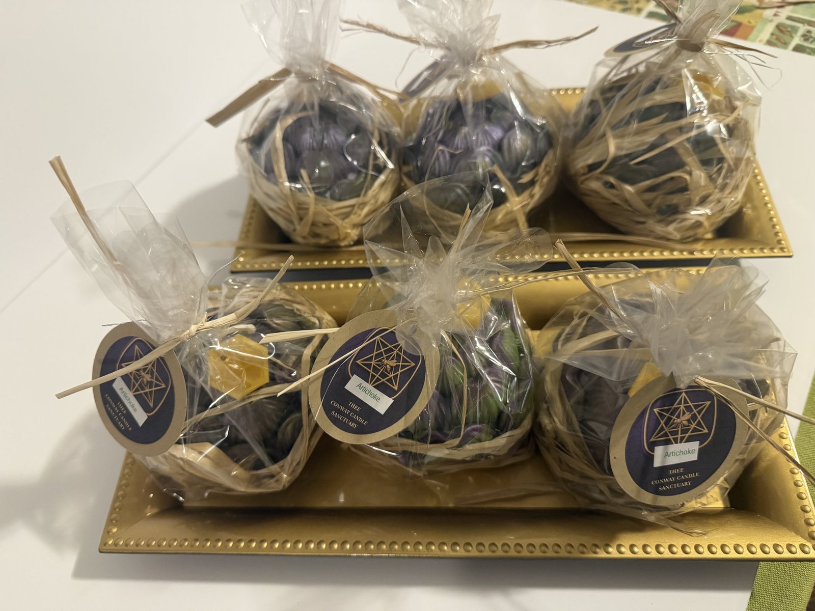 Maine beeswax artichoke candles wrapped with tags on gold trays · artichoke pack